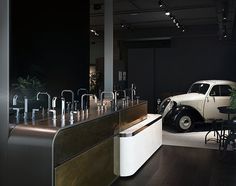 an old car is parked next to a bar in a dark room with chairs and tables