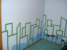 a room with a skateboard painted on the wall and green tape around the walls