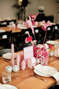 the table is set with pink napkins and place settings for guests to sit at