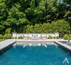 a pool surrounded by lush green trees and shrubbery is shown in this backyard photo