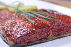 a piece of meat on a white plate with green garnish