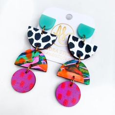 two pairs of colorful earrings with black and white spots on the bottom, one has a purple