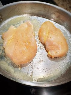 two pieces of chicken cooking in a pan