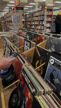 a person is holding an old record player in a library filled with books and vinyl records