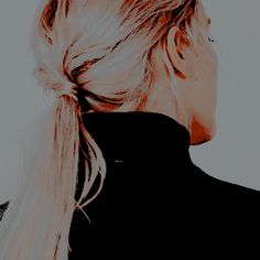 a woman with long blonde hair wearing a black shirt and ponytail in front of her face