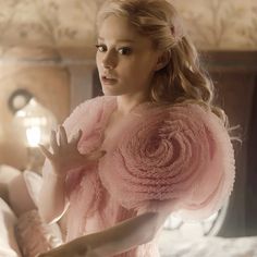 a woman in a pink dress standing next to a bed