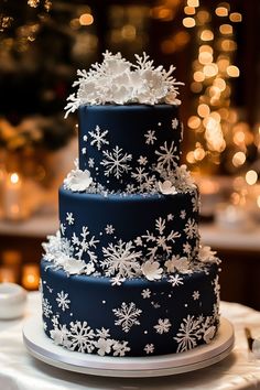 a three tiered blue and white wedding cake with snowflakes on the side