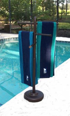 two towels are hanging on a towel rack by the pool