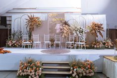 an arrangement of flowers and chairs on a stage set up for a wedding or special event