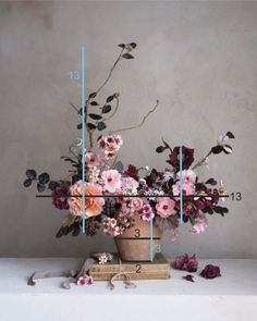 a vase filled with lots of flowers on top of a white table next to a ruler