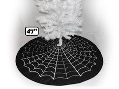 a black and white photo of a spider web on a round tablecloth with a tree in the center