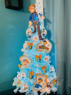 Blippi themed christmas tree decorated with blue and orange garland, ornaments and blippi cut outs Tree Deck, Toddler Slide, Homemade Ornaments, Plush Backpack, Orange Garland, Tree Topper, Blue And Orange, Tree Toppers, 2 Colours