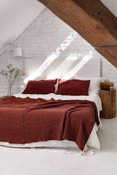 a bedroom with white brick walls and red bedspread on the bed in it