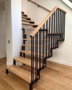 a wooden staircase with black railing and handrails in an empty room next to a white wall