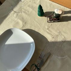 a white plate and some silverware on a table with a green tree in the middle