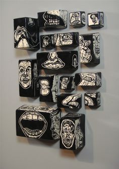 a group of black and white tiles with faces on them are hanging on the wall