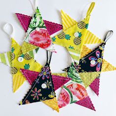 a group of colorful triangle shaped ornaments hanging from strings on a white table with scissors