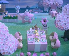 a table set up in the middle of a garden with pink flowers and decorations on it