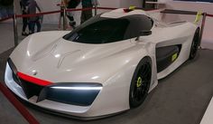 a white sports car is on display in a showroom with people looking at it