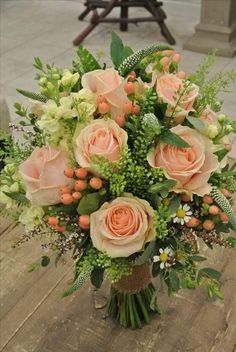 a bouquet of peach roses and greenery on a table