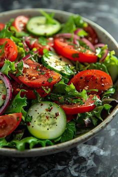 a salad with tomatoes, cucumbers and onions in a bowl on a table