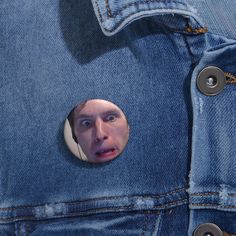 a man's face is seen through a hole in a jean jacket with buttons