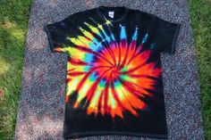 a tie - dyed t - shirt laying on the ground with grass in the background