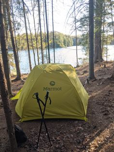 a tent set up in the woods next to a lake