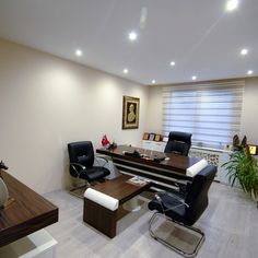 an office with two black leather chairs and a wooden table in the middle of it