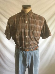 vintage 1950s men's button up shirt 'Imported Fabric' cotton slub fabric selvedge button up front loop collar collar stays (removable) brown w/black thread undertone  w/grays, yellow, browns pin stripes plaid pattern short sleeve straight hem 2 breast pockets good vintage condition, light wear- tiny scrape hole to back shoulder but has lined fabric underneath upper right back black thread nubs-see photos (slub fabric is characterized by light 'irregularities' in fabric threads/weave) labeled siz Brown Cotton Short Sleeve Shirt For Spring, Brown Cotton Shirt For Summer, Spring Brown Cotton Short Sleeve Shirt, Brown Cotton Summer Shirt, Classic Plaid Cotton Short Sleeve Shirt, Classic Plaid Short Sleeve Shirt For Summer, Classic Cotton Short Sleeve Plaid Shirt, Brown Short Sleeve Shirt With Button Closure For Summer, Brown Cotton Short Sleeve Shirt For Summer