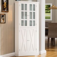 a tall white cabinet sitting in the corner of a living room next to a dining room table