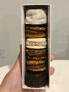 a hand holding an open box filled with donuts