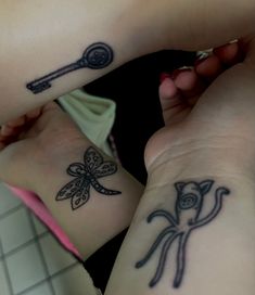 two girls with matching tattoos on their arms holding keys and key to each other's heart