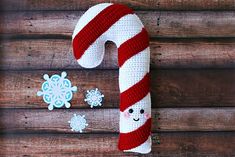 a crocheted candy cane sitting on top of a wooden table next to snowflakes