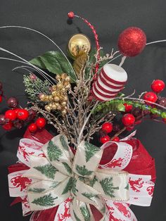 a red and white bow with christmas decorations on the top is sitting in front of a black background