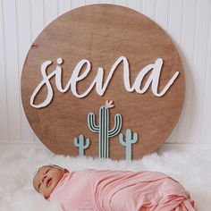 a baby is laying down in front of a wooden sign that says, senda