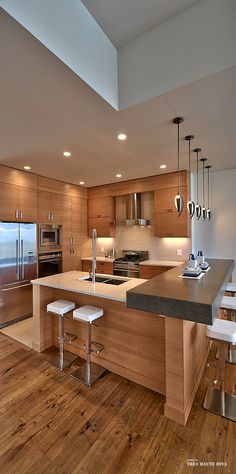 a modern kitchen with wooden floors and stainless steel appliances, including an island countertop