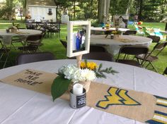 a vase with flowers on top of a table at a graduation party in the park