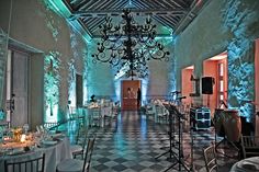 a room filled with tables and chairs covered in white tablecloths under a chandelier