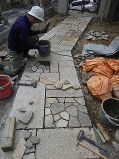 a man sitting on top of a stone floor next to buckets and shovels