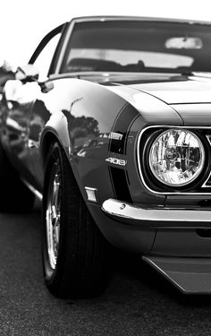 a black and white photo of the front end of a classic mustang parked in a parking lot