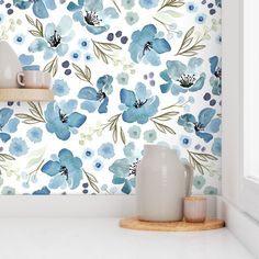 a blue flowered wallpaper with white vases on the counter and shelves in front