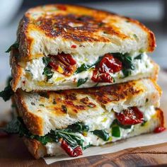 two grilled cheese sandwiches stacked on top of each other with tomatoes and spinach