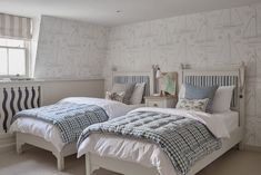 two twin beds in a bedroom with blue and white wallpapers on the walls