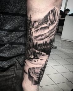 a man's arm with mountains and trees on it