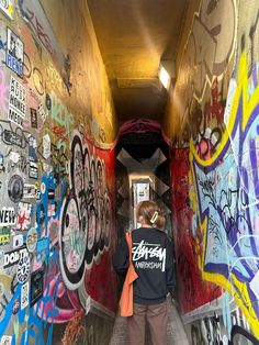 a person walking down a tunnel covered in graffiti