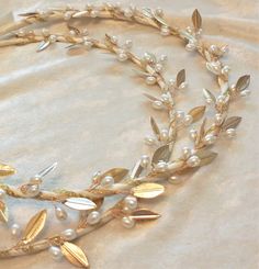 a close up of a necklace with pearls and leaves on a white cloth covered surface