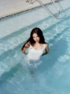 a woman standing in the water next to a swimming pool