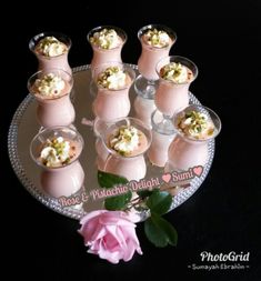 small desserts are arranged on a plate with pink flowers in vases next to them