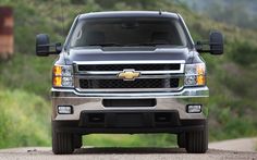 the front end of a silver truck on a dirt road